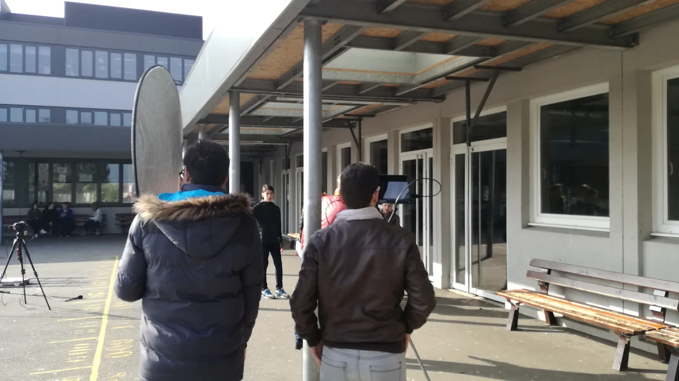 Les jeunes réalisateurs et un réflecteur de lumière lors d’une prise en extérieur.