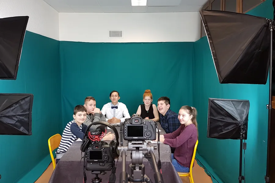Les élèves de la classe ULIS sur le plateau de leur journal télévisé, devant un fond de studio turquoise.