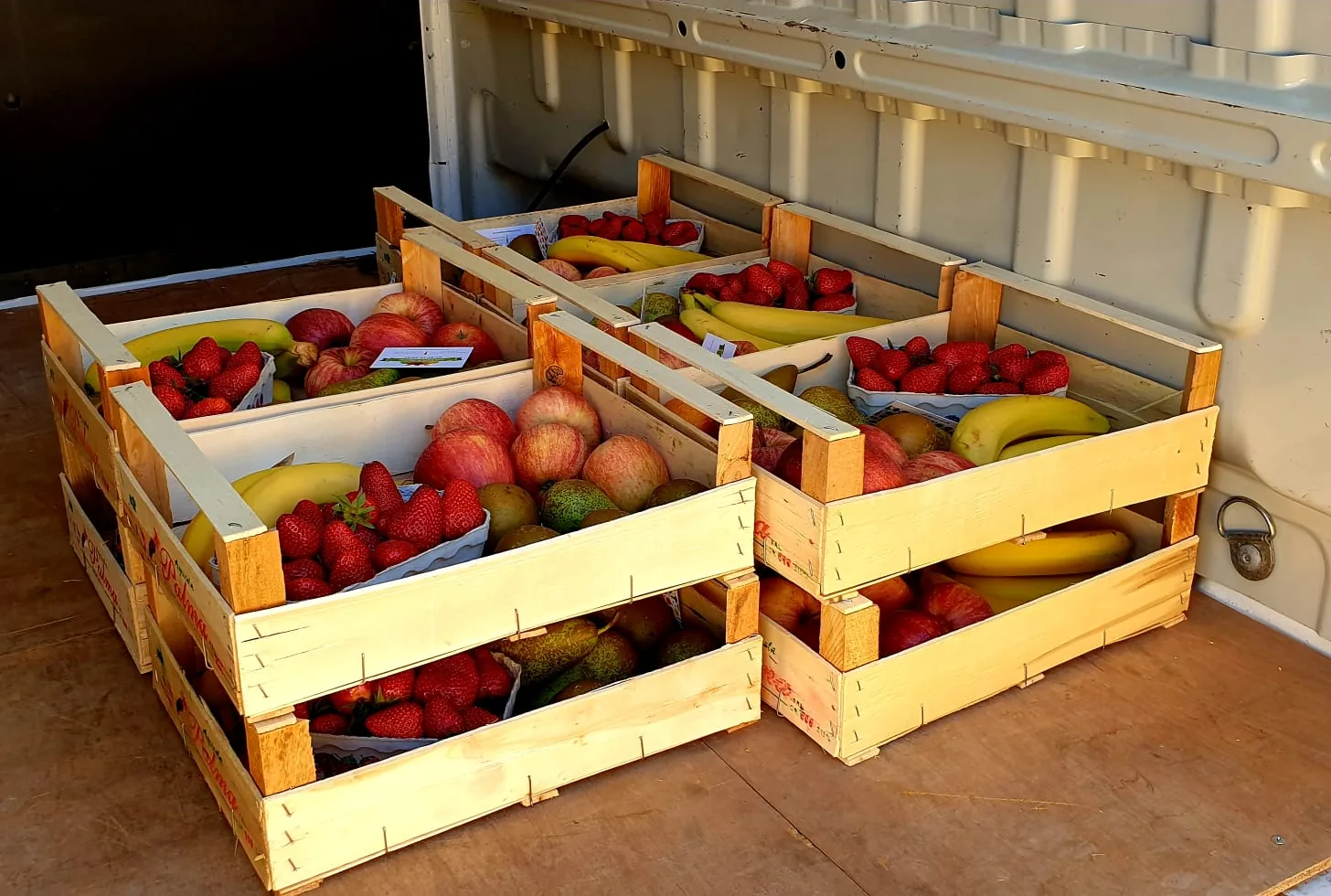 Des cagettes de fruits frais, pommes, fraises et bananes, préparées pour l’hôpital.