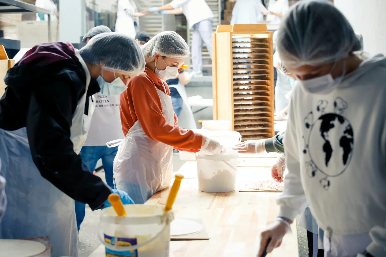 Garnissage des tartes flambées à la chaîne par les bénévoles.